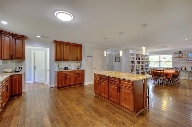 2944 Berry Rd, Loganville, GA 30052 - kitchen featuring backsplash, hanging light fixtures, hardwood / wood-style flooring, light stone counters, and recessed lighting