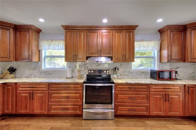 2944 Berry Rd, Loganville, GA 30052 - kitchen featuring brown cabinetry, decorative backsplash, under cabinet range hood, and stainless steel range with electric cooktop