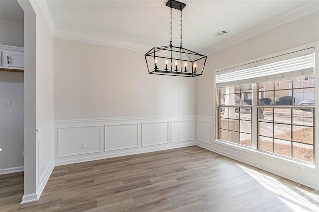 unfurnished dining area with crown molding and hardwood / wood-style flooring