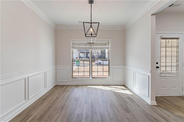 unfurnished dining area with crown molding and light wood-type flooring