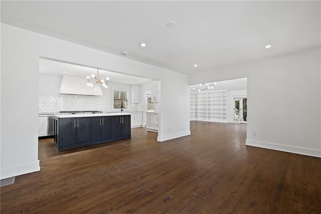 unfurnished living room featuring dark hardwood / wood-style flooring, a notable chandelier, and built in features