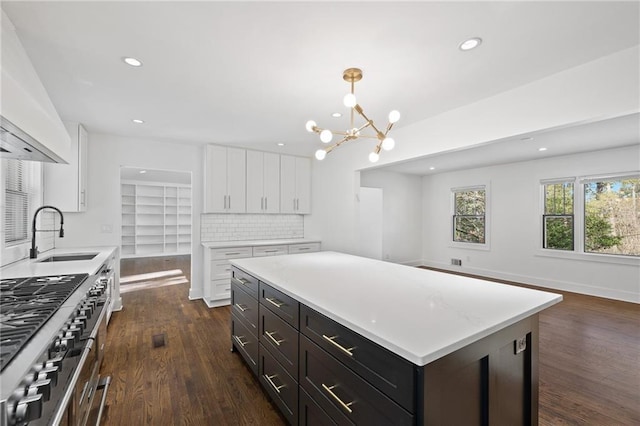 kitchen featuring pendant lighting, white cabinetry, sink, double oven range, and a center island