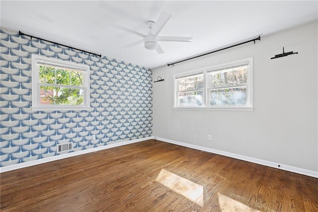 spare room featuring wood-type flooring, a healthy amount of sunlight, and ceiling fan