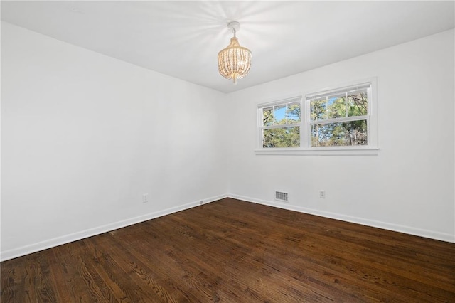 empty room featuring hardwood / wood-style floors and a notable chandelier