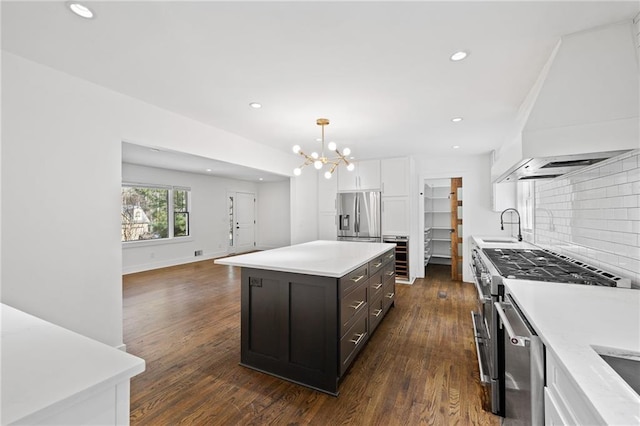 kitchen with pendant lighting, appliances with stainless steel finishes, white cabinetry, custom range hood, and a kitchen island