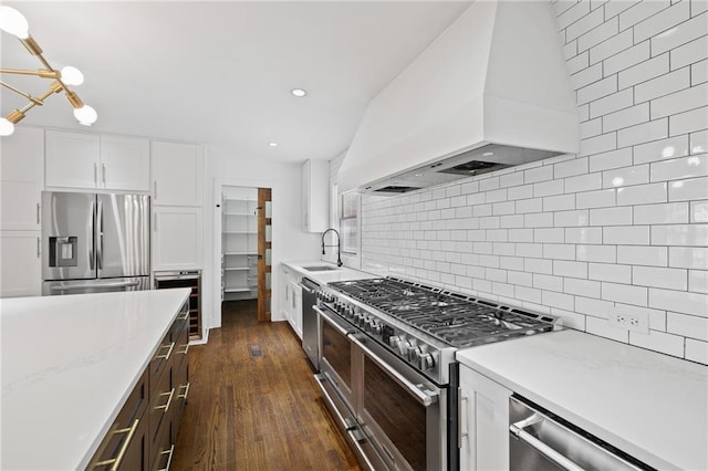 kitchen featuring sink, custom exhaust hood, white cabinetry, tasteful backsplash, and appliances with stainless steel finishes