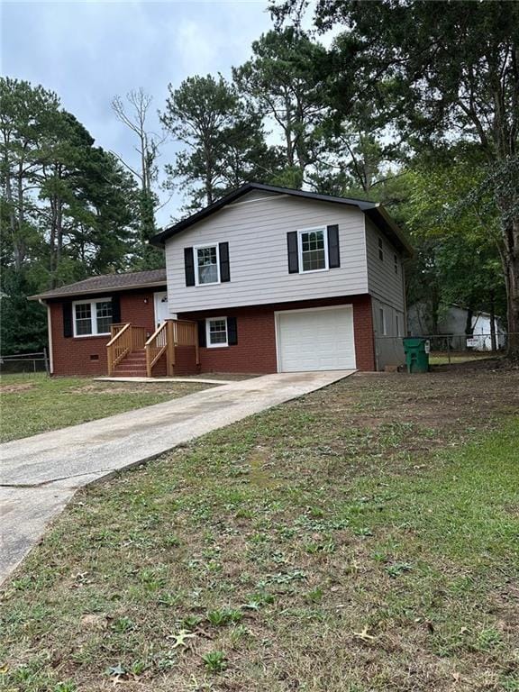 tri-level home with concrete driveway, a front lawn, fence, a garage, and brick siding