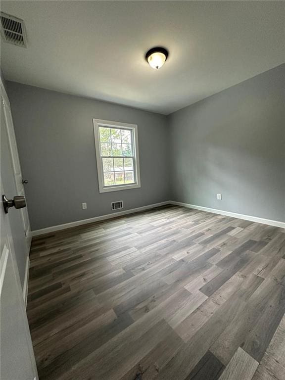 unfurnished room with baseboards, wood finished floors, and visible vents