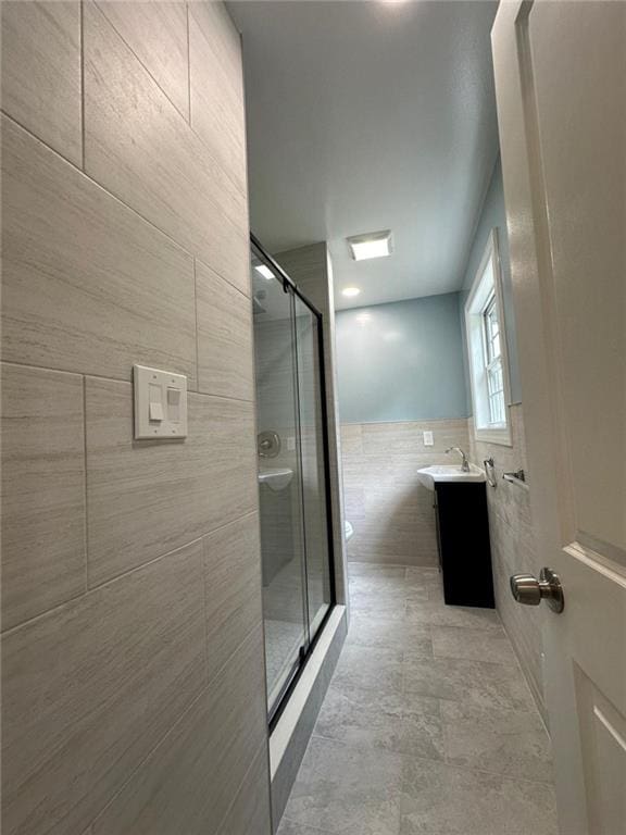 bathroom featuring a shower stall, toilet, vanity, and tile walls