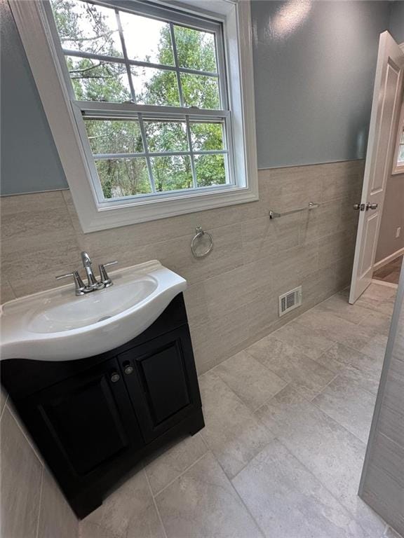 bathroom featuring tile walls, visible vents, a wealth of natural light, and vanity