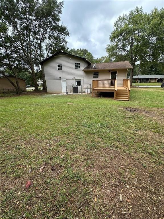 rear view of property with a wooden deck, a yard, and central air condition unit
