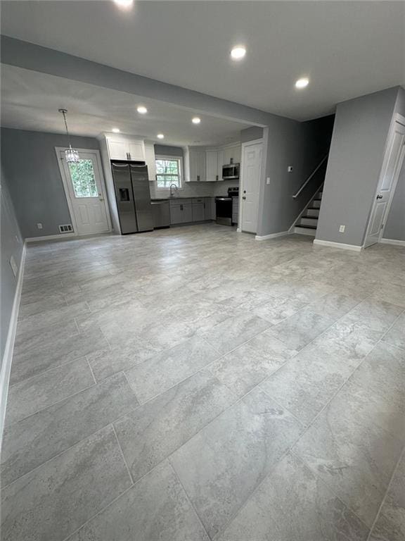 unfurnished living room with baseboards, stairs, and recessed lighting
