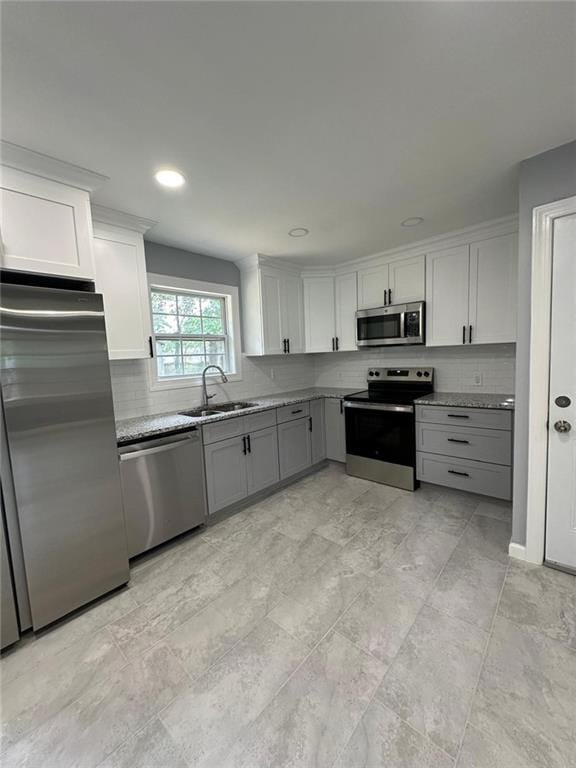 kitchen featuring stainless steel appliances, a sink, gray cabinetry, tasteful backsplash, and white cabinetry