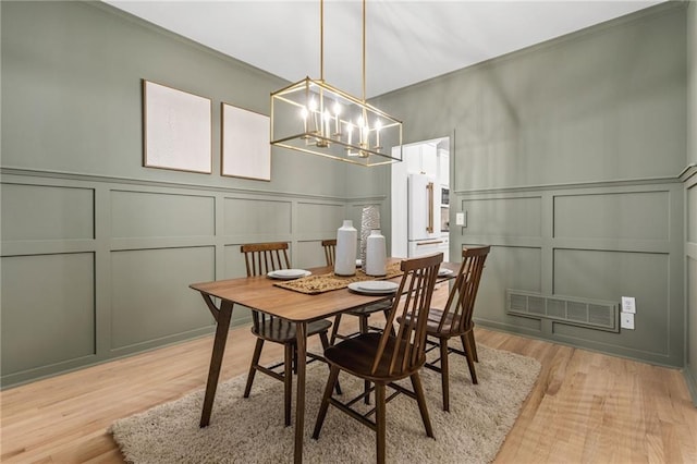 dining area with light hardwood / wood-style floors and a chandelier