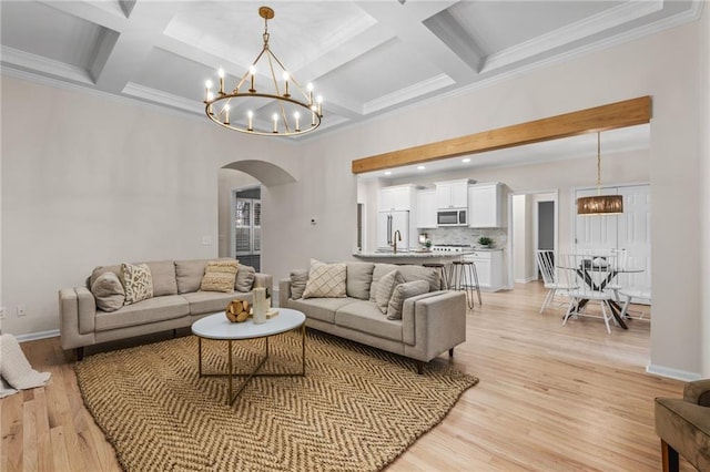 living room featuring coffered ceiling, beamed ceiling, a notable chandelier, and light wood-type flooring