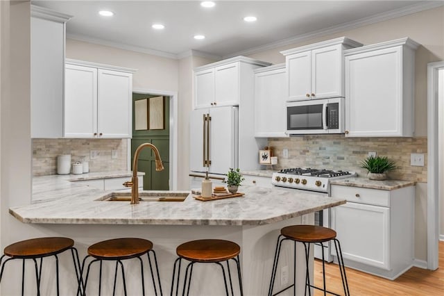 kitchen with stove, high end white refrigerator, a breakfast bar area, and white cabinets