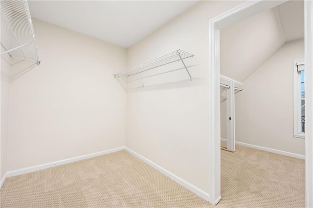 spacious closet with light carpet and vaulted ceiling