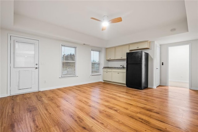 kitchen featuring ceiling fan, black refrigerator, light hardwood / wood-style flooring, and cream cabinetry