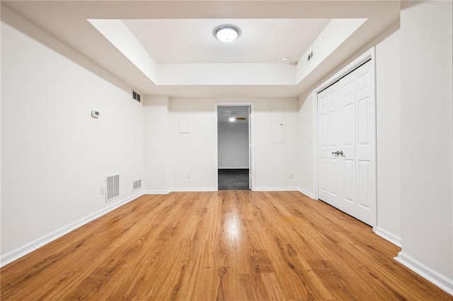 unfurnished bedroom featuring light hardwood / wood-style floors, a closet, and a raised ceiling