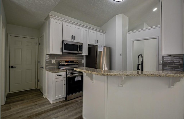 515 Allens Landing Ct, Lawrenceville, GA 30045 - kitchen featuring stainless steel appliances, light stone counters, a kitchen breakfast bar, white cabinets, and a textured ceiling