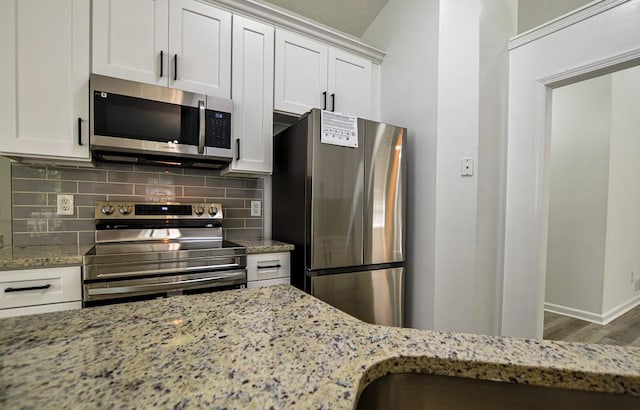 515 Allens Landing Ct, Lawrenceville, GA 30045 - kitchen with stainless steel appliances, light stone countertops, backsplash, wood finished floors, and baseboards