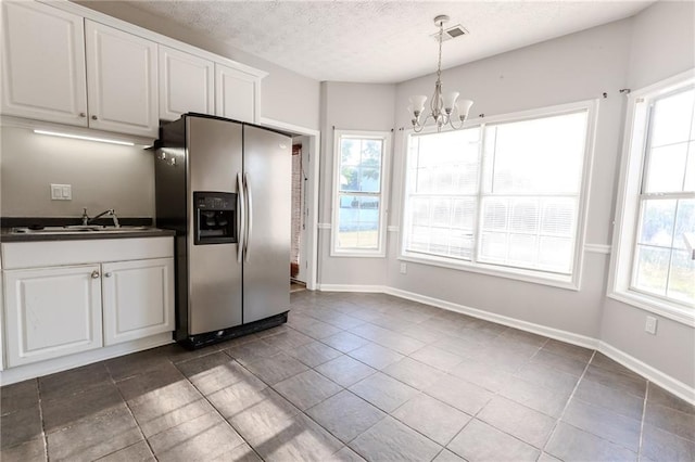 kitchen featuring white cabinetry, hanging light fixtures, stainless steel fridge, and plenty of natural light