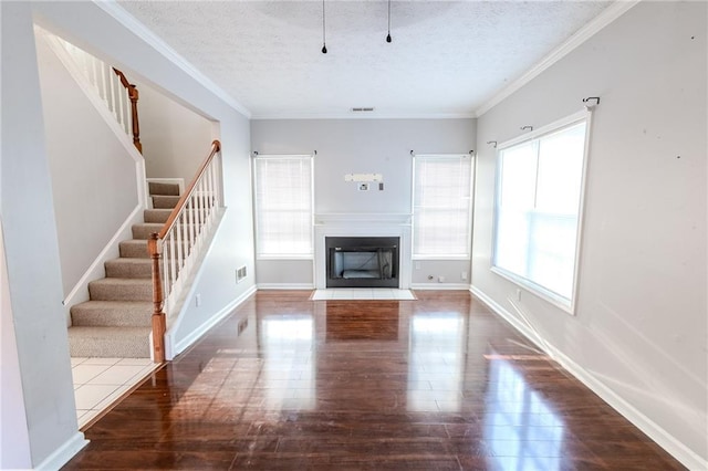 unfurnished living room featuring dark wood-type flooring, crown molding, and a textured ceiling