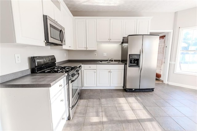 kitchen with white cabinetry, sink, stainless steel appliances, and light tile patterned flooring