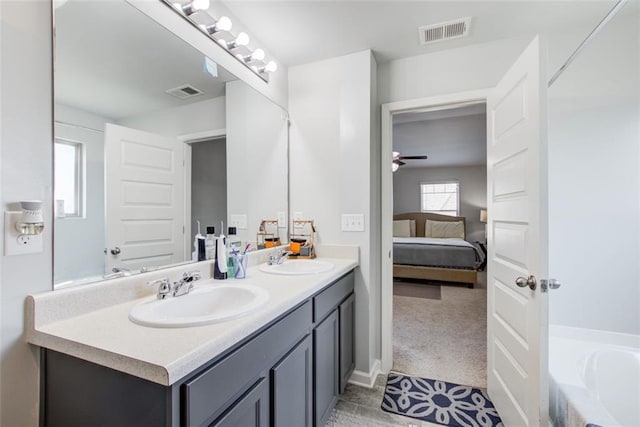 ensuite bathroom with visible vents, a sink, a garden tub, and double vanity