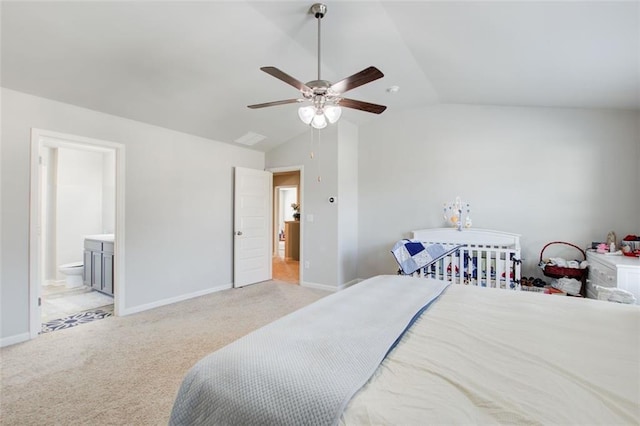 bedroom featuring vaulted ceiling, baseboards, ensuite bathroom, and light colored carpet