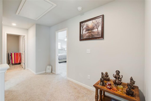 corridor with carpet floors, attic access, and baseboards