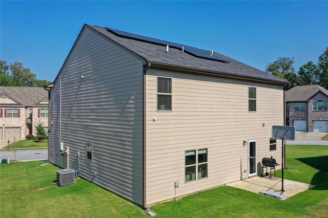 back of house featuring a patio area, solar panels, central AC, and a yard