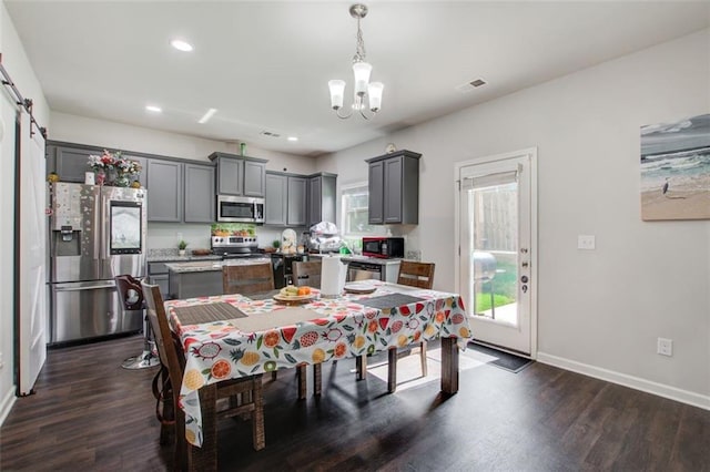 dining space featuring a healthy amount of sunlight, dark wood finished floors, visible vents, and a barn door