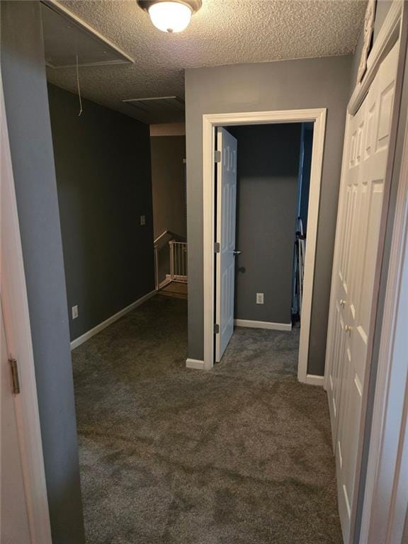 hall with a textured ceiling and dark carpet