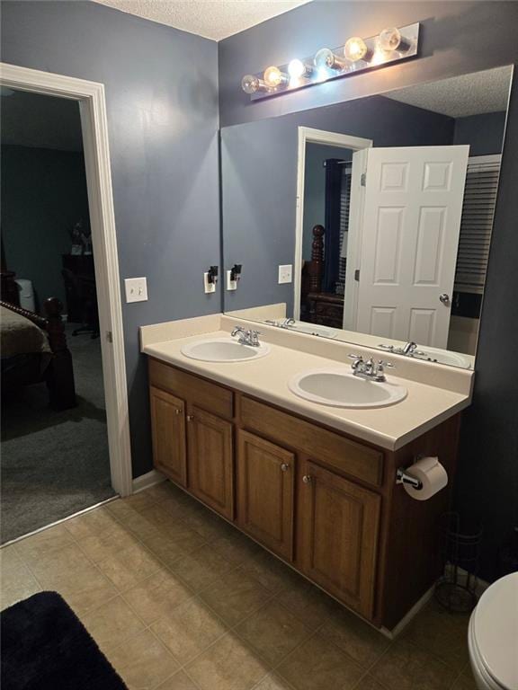 bathroom featuring vanity, tile patterned flooring, a textured ceiling, and toilet