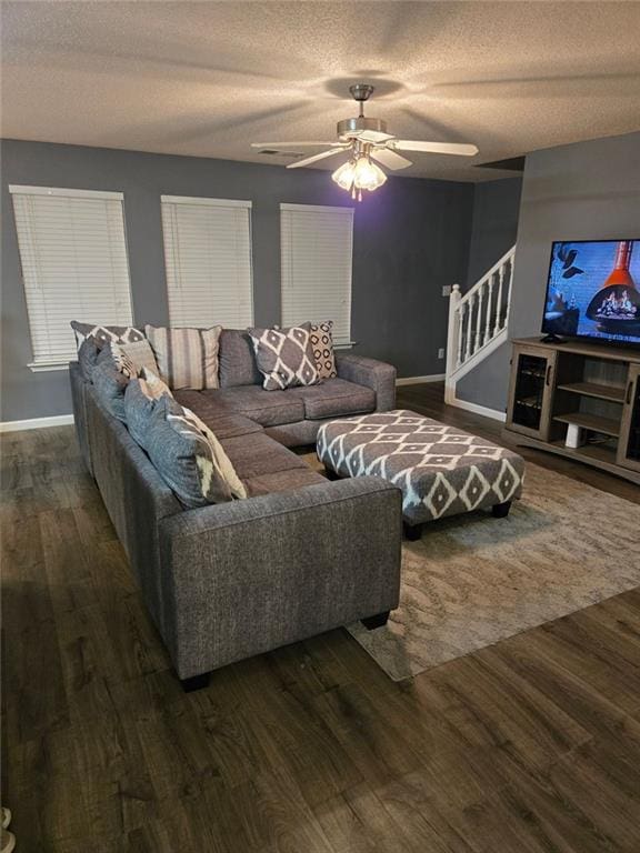 living room featuring ceiling fan, dark hardwood / wood-style flooring, and a textured ceiling