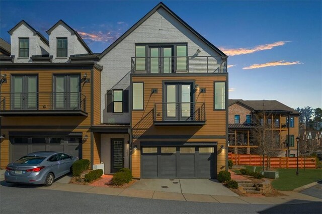 view of front of home with a balcony, french doors, and a garage