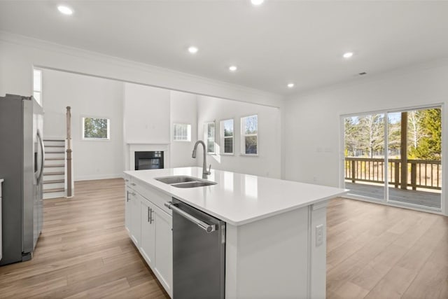 kitchen featuring an island with sink, white cabinetry, sink, stainless steel appliances, and crown molding