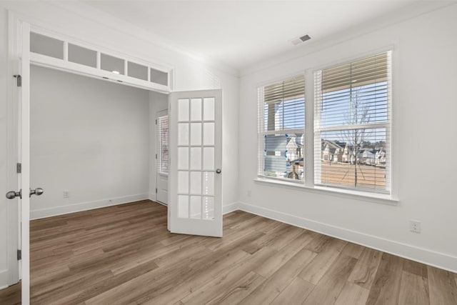 empty room with crown molding, hardwood / wood-style floors, and french doors