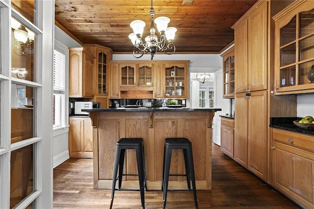 kitchen featuring a breakfast bar area, dark countertops, an inviting chandelier, white microwave, and wood ceiling