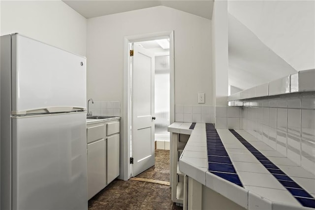 bathroom featuring vaulted ceiling, stone finish floor, a sink, and decorative backsplash