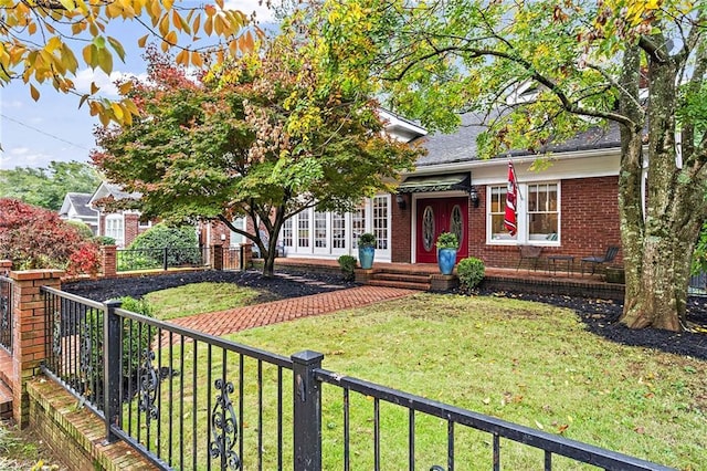 view of property hidden behind natural elements with a fenced front yard, a front yard, and brick siding