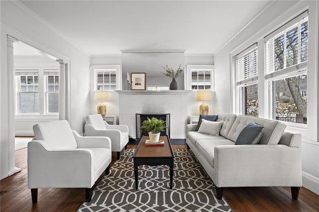 sitting room featuring a wealth of natural light, crown molding, wood finished floors, and ornate columns