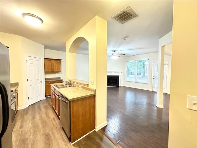 kitchen with appliances with stainless steel finishes, wood-type flooring, sink, and ceiling fan