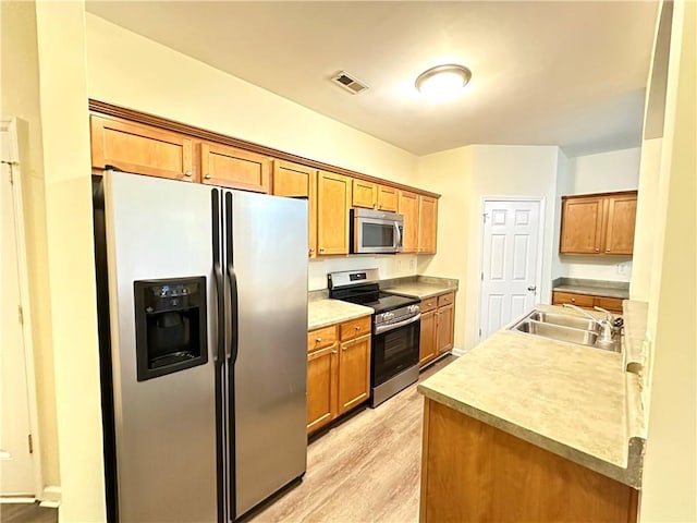 kitchen featuring appliances with stainless steel finishes, sink, and light hardwood / wood-style flooring