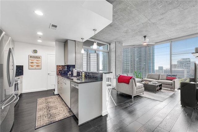 kitchen featuring pendant lighting, backsplash, stainless steel appliances, ceiling fan, and dark hardwood / wood-style floors