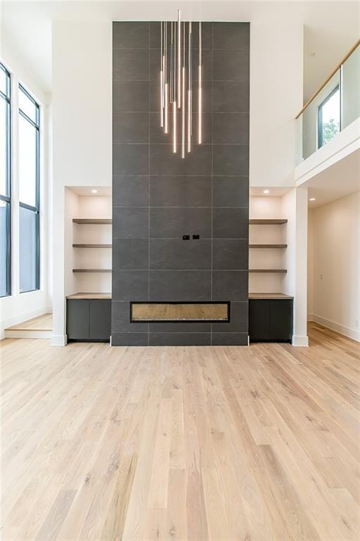 unfurnished living room featuring built in features, a wealth of natural light, and hardwood / wood-style floors