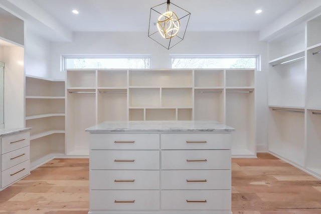 spacious closet featuring light hardwood / wood-style floors and a chandelier