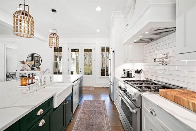 kitchen featuring stainless steel appliances, a sink, hanging light fixtures, custom exhaust hood, and white cabinetry