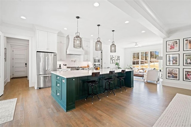 kitchen with wood finished floors, light countertops, white cabinets, appliances with stainless steel finishes, and recessed lighting